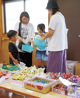 ずらりと並んだ駄菓子を選ぶ親子連れ