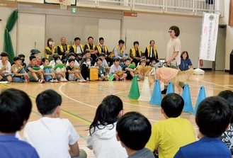 カラーコーンをよけて歩く三宅さんとウニカを熱心に見つめる児童たち