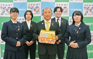 オレンジリボンを手渡した学生、生徒らと市長（中央）