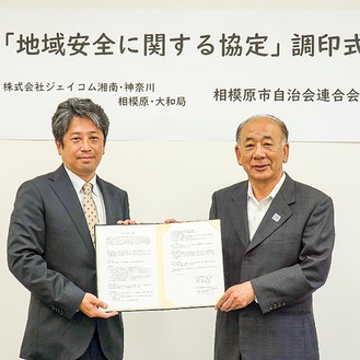 協定書を交わす竹田会長（右）と同局の加藤局長（左）。21日、千代田の同局社屋で