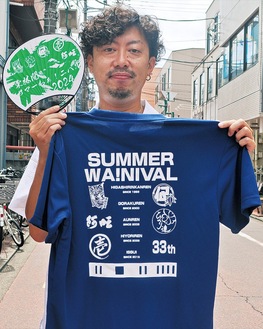 自身がデザインしたうちわとＴシャツを持つ石田さん