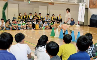 カラーコーンをよけて歩く三宅さんとウニカを熱心に見つめる児童たち