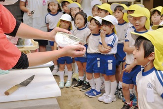 角上魚類のスタッフがさばいたブリの頭をのぞき込む園児