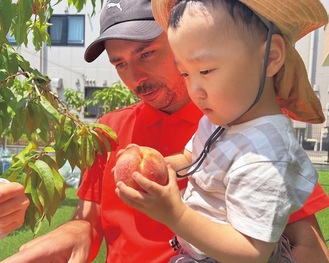 先生と一緒に採った大きな桃を手にする園児