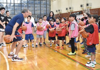 ドリブル練習前にコーチの英語の解説に耳を傾ける市内小学生ら