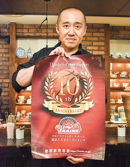 10周年記念ポスターを持つ永塚さん