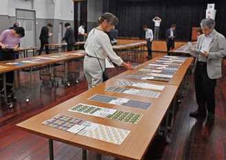 講堂で一つひとつ柄を審査される応募作品