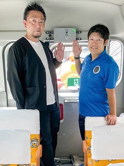 車内に設置された装置を指す鈴木さん（左）と籾山さん