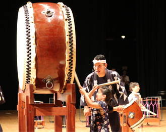 三枝さんに教わり、太鼓をたたく子ども＝提供