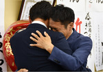 おえつをあげて抱き合う綱嶋洋一県議（左）と橘川氏（右）