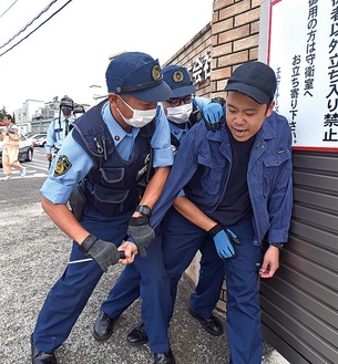 工場入口で取り押さえられる犯人役