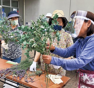 講師の大貫さんからブーケづくりのコツを教わる参加者。会場一帯にハーブの香りが立ち込めた。