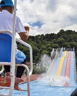 滑り台から水しぶきを高くあげて水に飛び込む