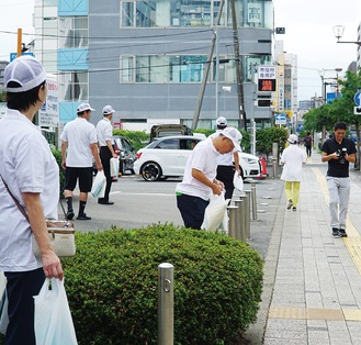 グッズを手に持ち道行く人に声がけする会員