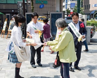 通行人に啓発品を手渡す学生