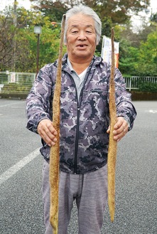 試し掘りをした自然薯を持つ山田会長