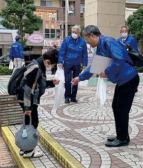 街頭広報でグッズを渡す参加者