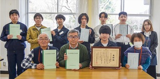 完成した冊子を手にする生徒と「歴史を楽しむ会」メンバー