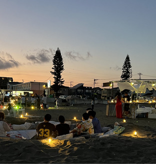 砂浜に設けられたソファーで夕景を楽しむ人たち