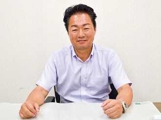 会社のデスクで父譲りの柔和な笑みを浮かべる鈴木さん