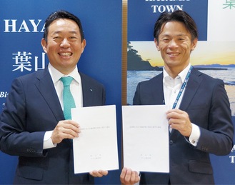 協定書を手に笑顔の石見社長（左）と山梨町長