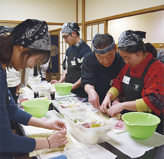 巻物を指導する板長の池田さん（右から２人目）