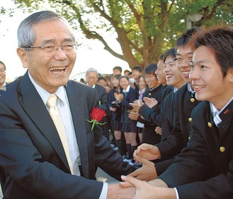 母校の湘南高校で在校生と握手を交わす根岸さん（左）（＝2010年11月、鵠沼神明）