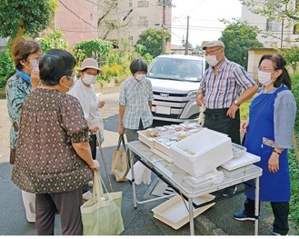 販売所で談笑する販売者と住民たち