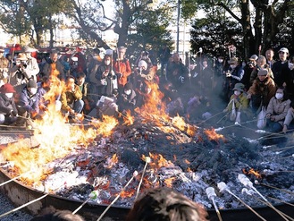 斎灯の火で団子を焼く参加者（提供写真）