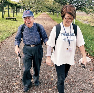 ヘルパーと共に笑顔で歩く宮崎さん（左）