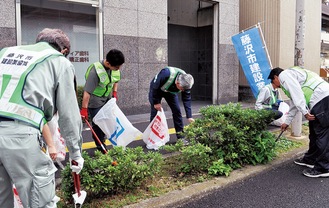 植え込みのごみを拾う会員たち