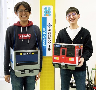 スクールの生徒が作った電車の模型を手にする運転士の鷲田さん(左)と別所さん