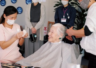 和やかな雰囲気の中で、フルメイクとヘアセットを受ける女性