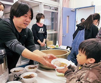 カレーを渡す高見さん（左）