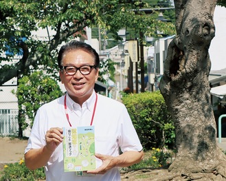 著書を持つ稲田さん。場所は表紙にも描かれる今泉台の公園