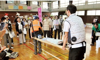 竹を活用した担架で小学生を搬送＝７日・山崎小体育館