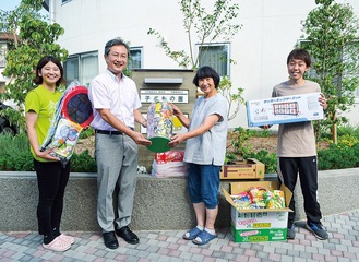 子どもの園で物品を手渡す藤江組合長（左から２人目）