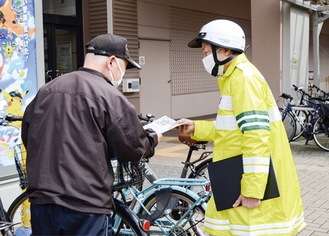 自転車利用者にチラシを手渡す警察官