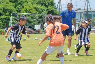 アンバサダーの坪井さんとはつらつプレーを見せた子どもたち＝８日、アルバック社グラウンド