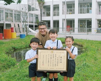 表彰状を掲げる園児たちと堀田園長