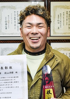 表彰状とトロフィーを手に喜ぶ秋山さん