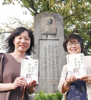 岡野金次郎の石碑前（湘南平）で書籍を持つ利英子さん（右）と遥さん