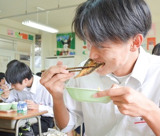 カマスのかば焼きにかぶりつく生徒