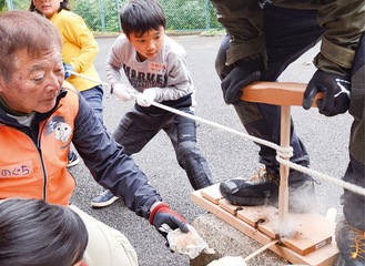 懸命に火おこしする児童