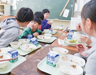 楽しそうに給食を食べる園児と児童