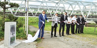 酒匂川右岸堤防に立てられた記念碑と関係者ら