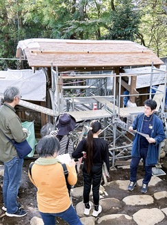 修復中の皆春荘表門の前で、芹澤さんから説明を聞く参加者