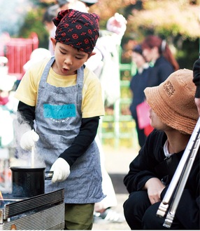 火で調理をする園児と、見守る保護者