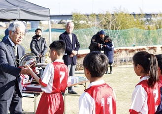 千村社長からトロフィーを受け取るＦＣ中井の選手ら