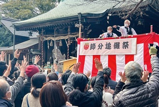 壇上からまかれる福豆に手を伸ばす参加者ら